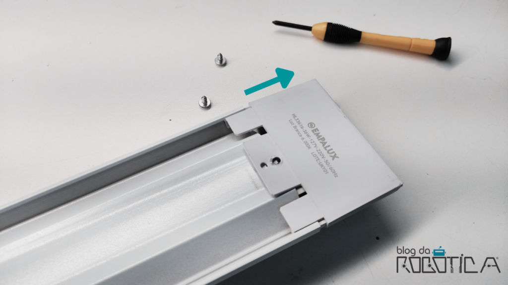 Imagem indicando o sentido correto para remover a tampa lateral da luminária.